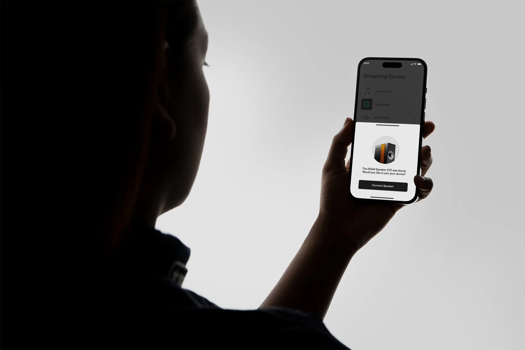 Close up of a woman holding an iPhone showing a speaker app.